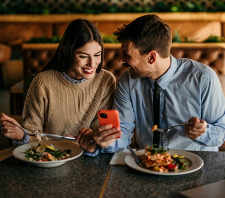 Clients qui déjeunent en regardant un téléphone