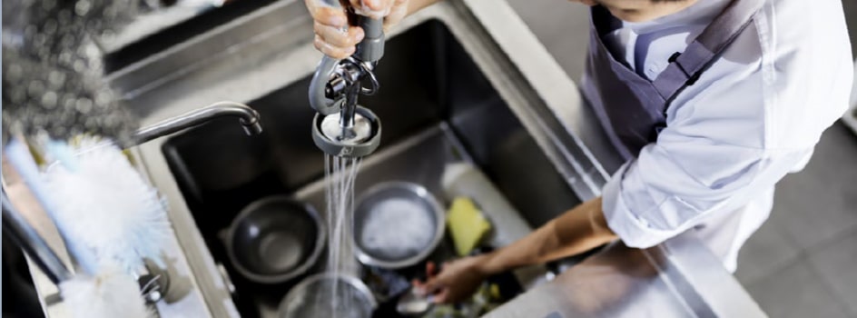 Le personnel fait la vaisselle dans un évier de cuisine professionnelle