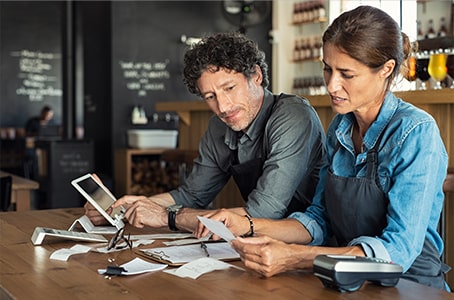 Deux restaurateurs qui calculent les coûts de leur activité