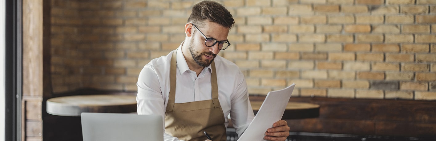Un restaurateur regarde un document devant son ordinateur