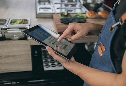 Un gérant utilise sa tablette pour les commandes passées