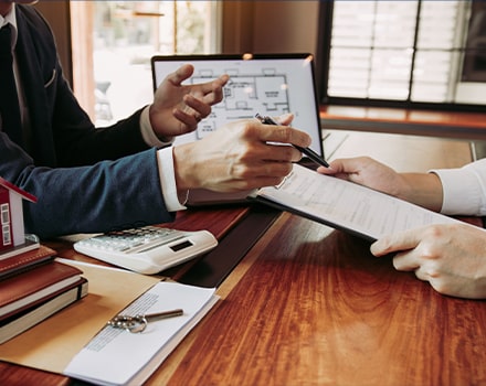 Deux personnes à un bureau regardant des plans et des devis