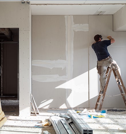 Homme sur une échelle faisant des travaux de rénovation énergétique