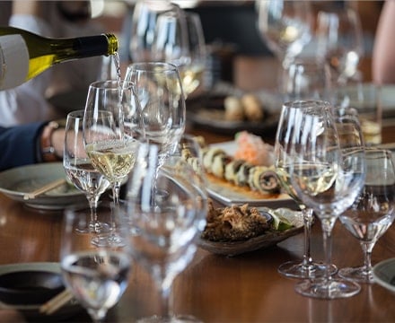 Serveur versant du vin blanc dans un verre à une table de restaurant