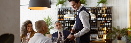 Serveur de restaurant présentant une bouteille de vin rouge à ses clients
