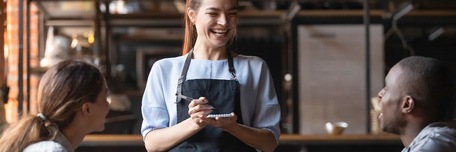 Serveuse de restaurant souriante plaisantant avec ses clients