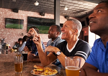 Supporters sportifs devant un hamburger et une bière au comptoir