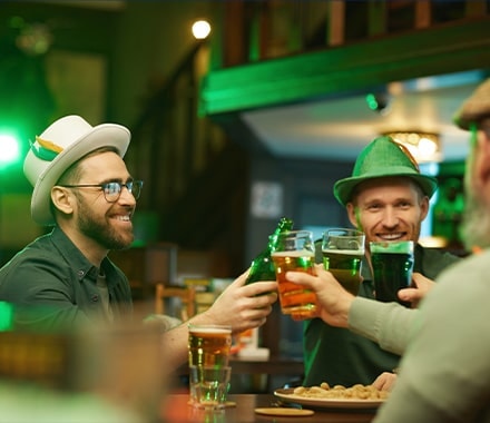 Hommes souriants avec des chapeaux traditionnels, buvant une bière dans un pub pour la St. Patrick