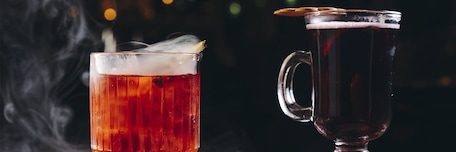 2 verres de cocktail de couleur rouge sur fond noir et fumée
