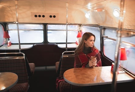 Femme dans un bus diner avec une tasse à la main