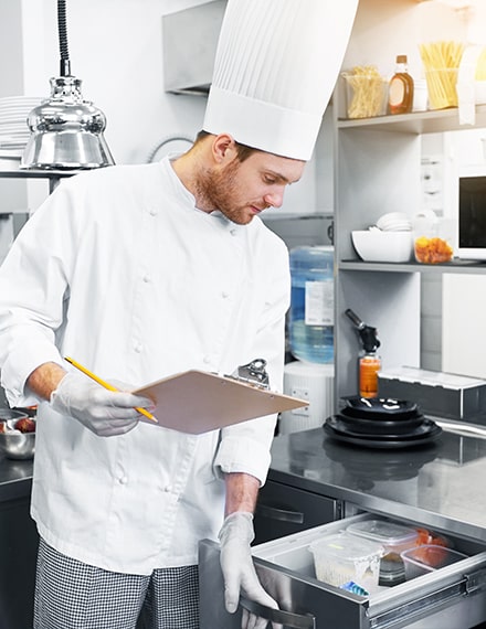 Chef de restaurant contrôlant le contenu d'un tiroir avec une liste