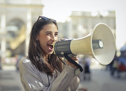 Femme souriante parlant dans un mégaphone