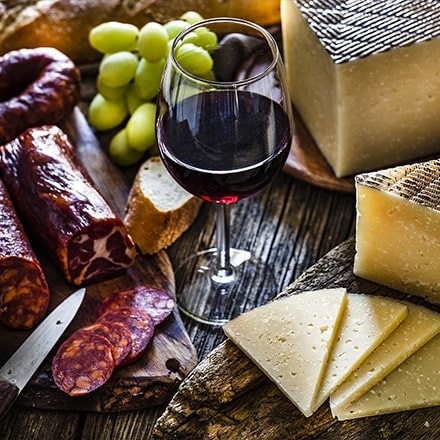 Fromage, chorizo, pain, raisin et vin rouge sur une table en bois rustique