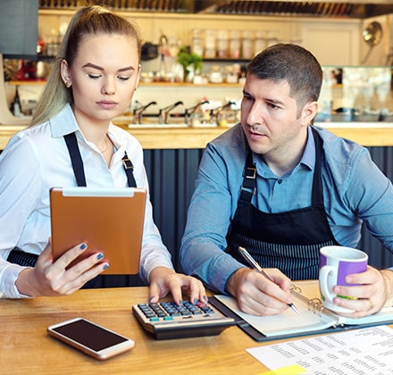 Restaurateurs faisant leur compte avec une calculatrice