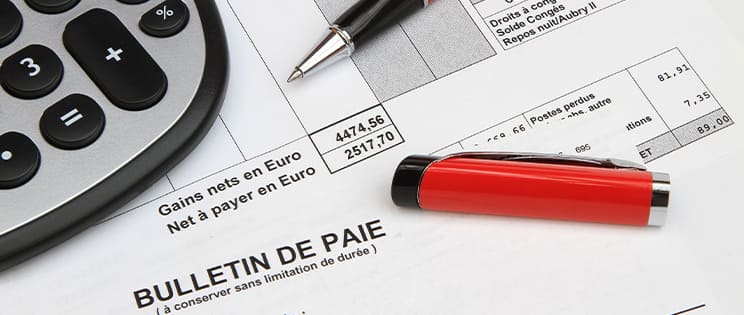 Stylo rouge posé sur un bulletin de paie