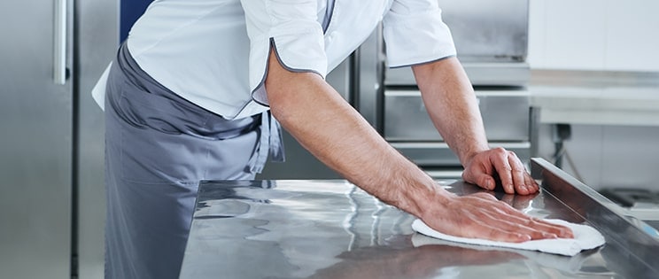 Serveur nettoyant un plan de travail en inox