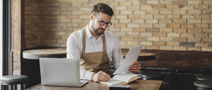 Un restaurateur regarde un document devant son ordinateur