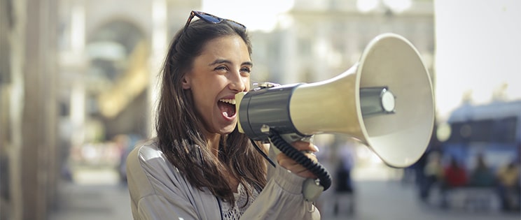 Femme souriante parlant dans un mégaphone