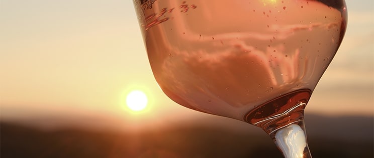 Verre de vin rosé devant le soleil couchant