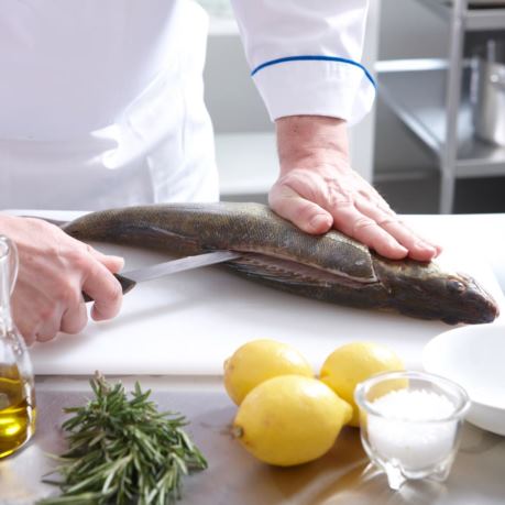 Bucatar sectioneaza biban pentru reteta cu peste