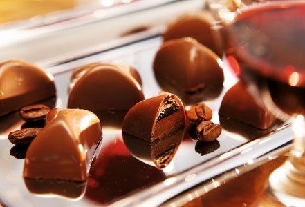 ciocolate, bomboane de ciocolata langa pahar cu vin rosu