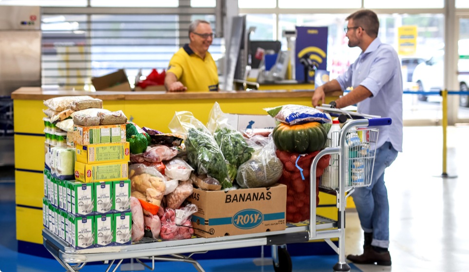 Cliente com carrinho cheio a pedir ajuda a colaborador makro