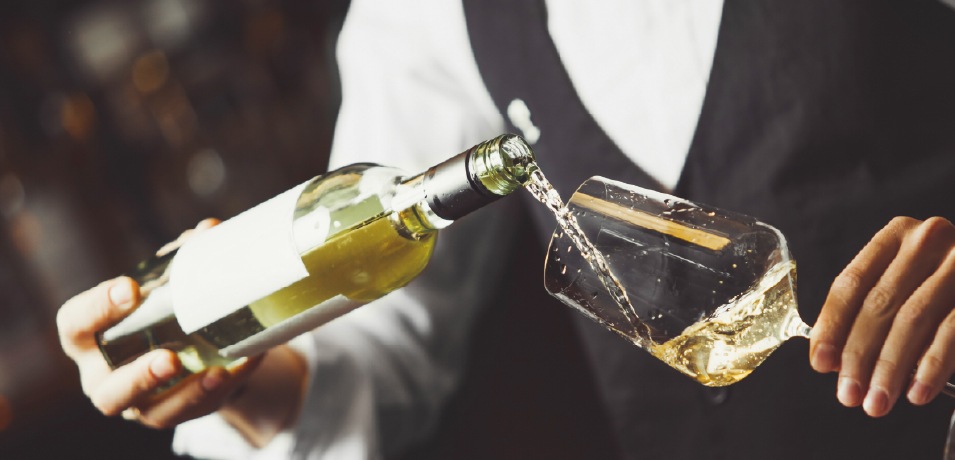 Homem a servir copo de vinho branco