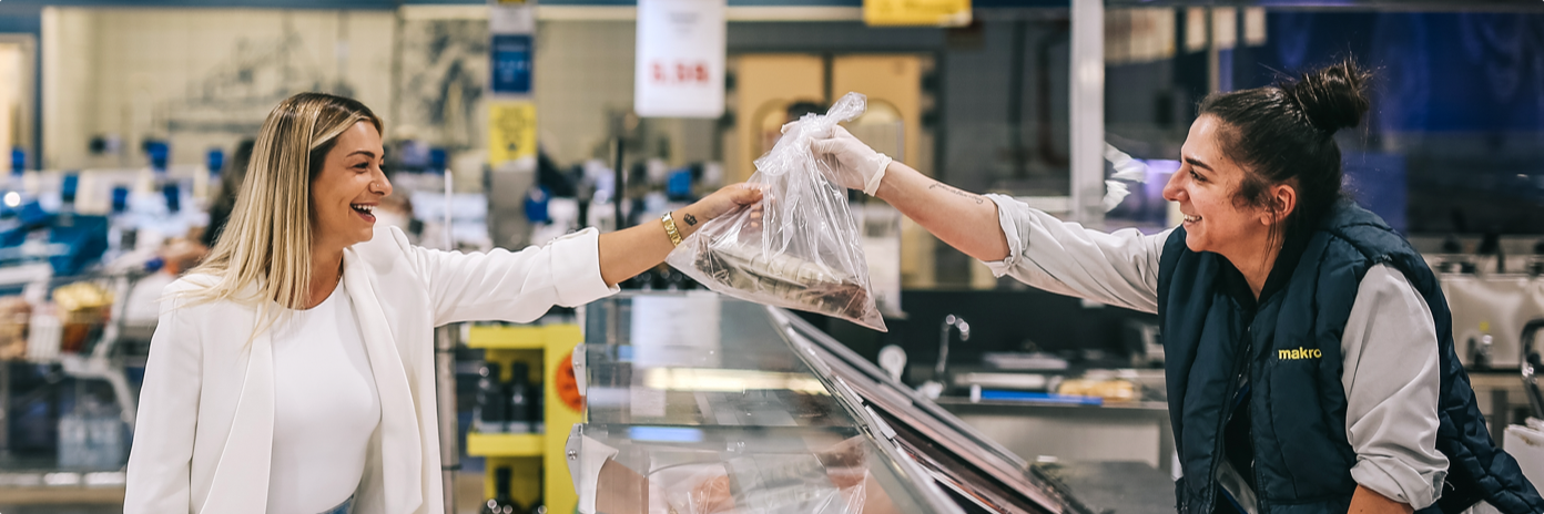 Cliente a receber pedido de peixe por funcionária makro