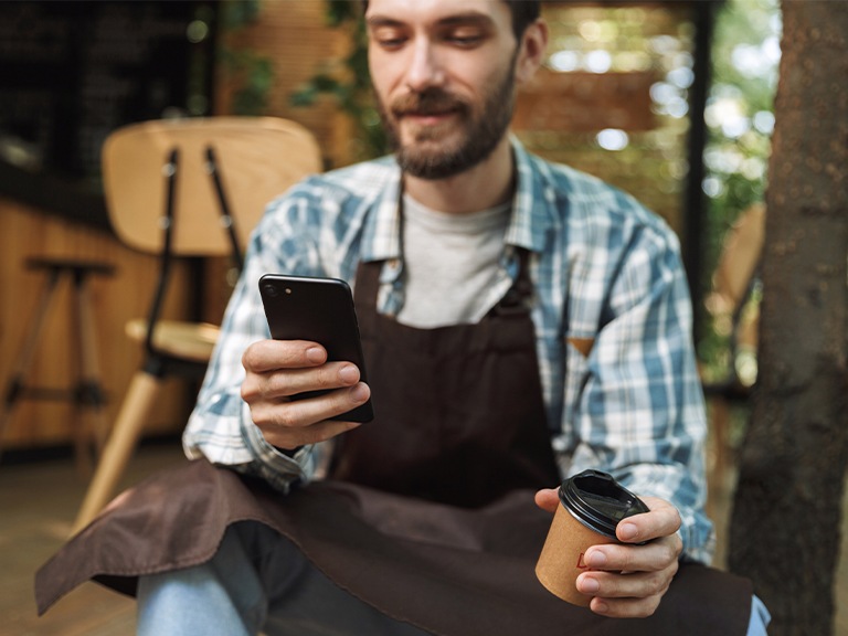 Homem sentado a mexer no telemóvel