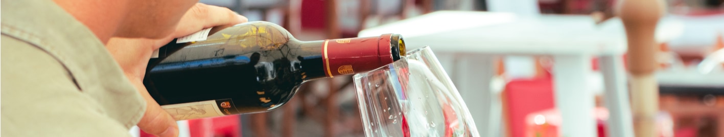 Homem a servir copo de vinho tinto