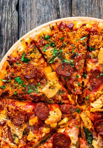 Pizza proaspăt coaptă cu chorizo, brânză și legume pe blat crocant