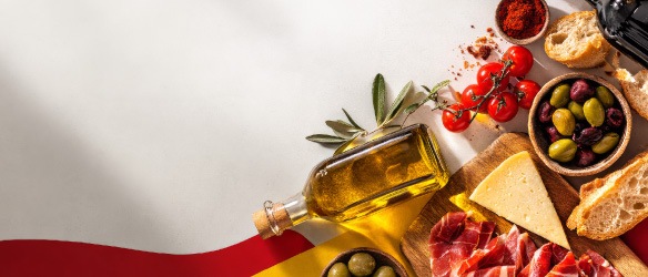 Selecție de produse spaniole – ulei de măsline, măsline, jamón, brânză, roșii și pâine – prezentate pe fundal în culorile Spaniei.