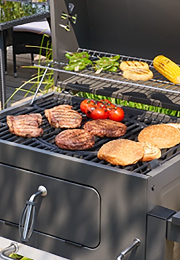 Grătar Memphis pe cărbune în timpul utilizării, cu carne, legume și chifle pregătite pe grătar.