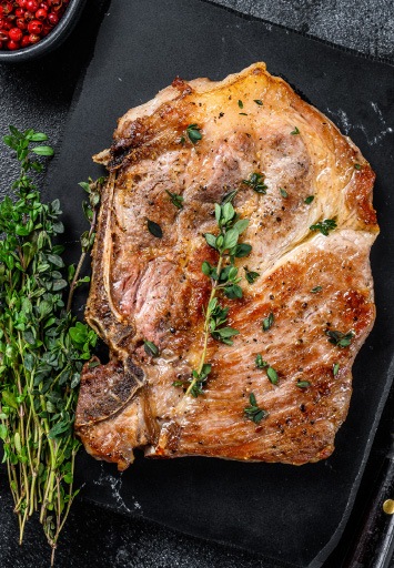 Ceafă de porc gătită la grill cu ierburi aromatice, preparat suculent pentru meniuri profesionale.