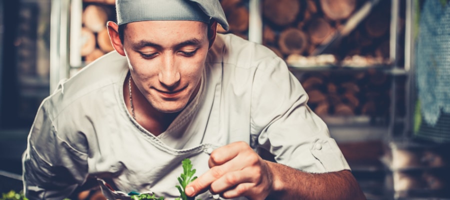 Un bucatar care pregateste cu atentie preparatul