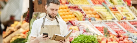 Un bărbat care ține o carte într-o mână, se uită pe telefon