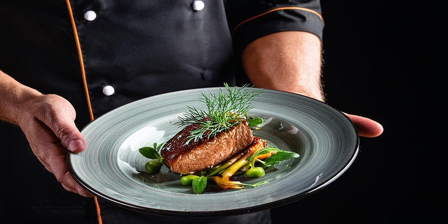 kuvar drži u rukama jelo na tanjiru