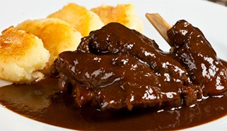 Dusené zajačie stehno s čiernou omáčkou a pečenými šúľancami