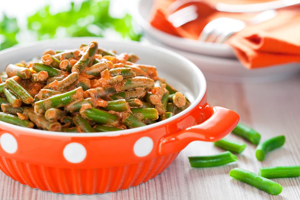 Зелена стручкова квасоля у вершковому соусі з томатами у керамічній мисці