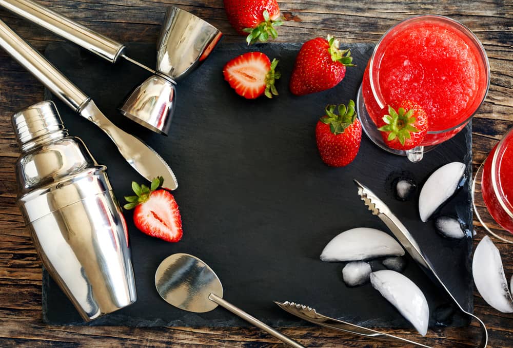 Інгредієнти для полуничного коктейлю: шейкер, барний інвентар, полуниця, лід та напій на слейтовій дошці