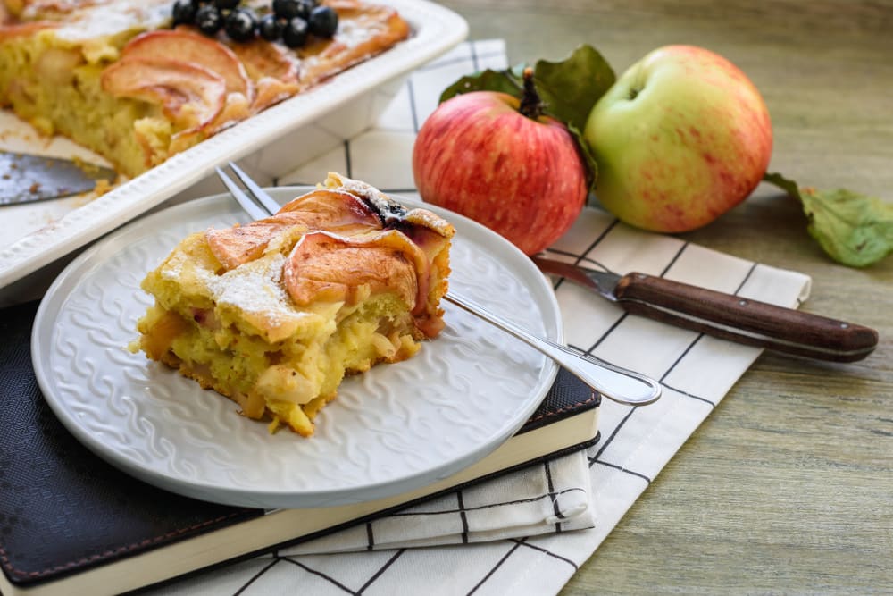 Шарлотка з грушами у формі на дерев’яному столі, поруч свіжі груші