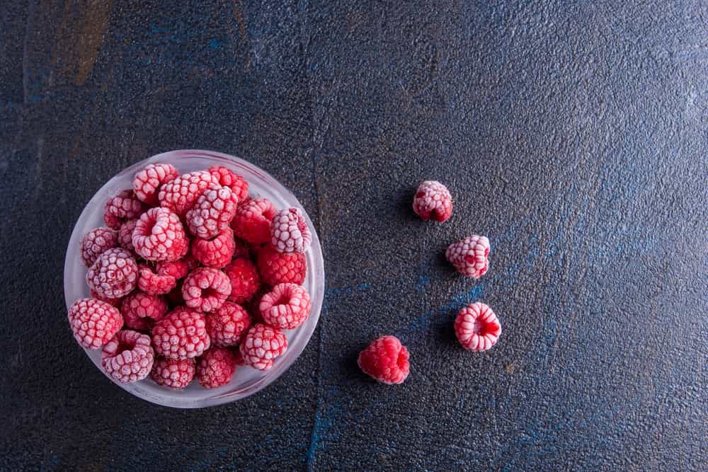 миска з замороженою малиною на темному фоні