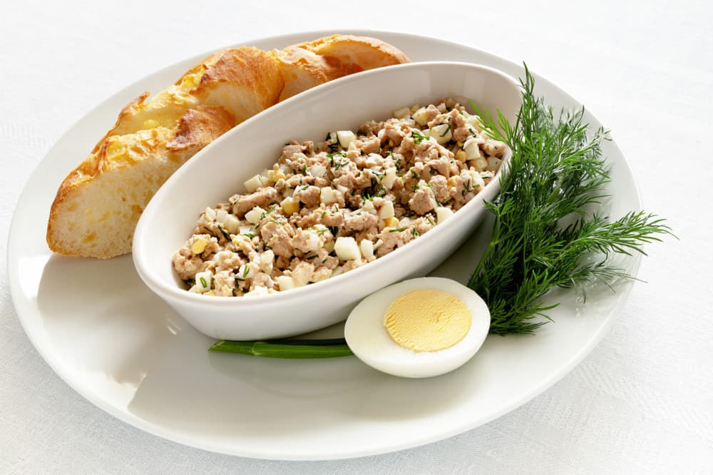 Салат із тунця, вареного яйця та зелені, поданий з багетом