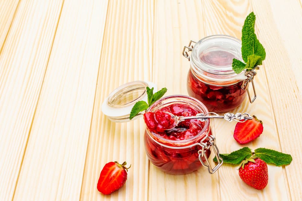 Дві скляні банки з полуничним варенням і свіжою м’ятою, поруч розрізані ягоди полуниці          Спросить ChatGPT