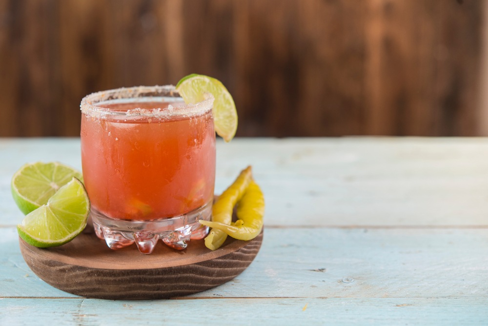 Червоний коктейль з лаймом і гострим перцем на дерев’яній підставці.