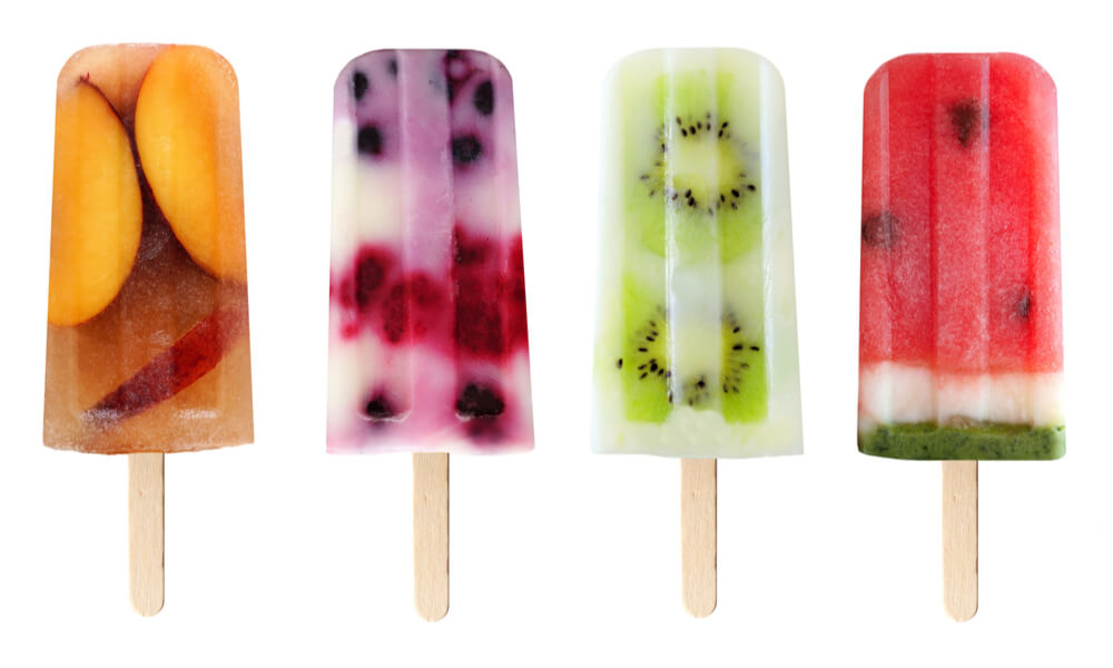 Чотири фруктові льодяники з персиком, ягодами, ківі та кавуном на білому фоні