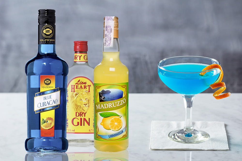 Блакитний коктейль у келиху поруч із пляшками Blue Curacao, джину та лимончелло