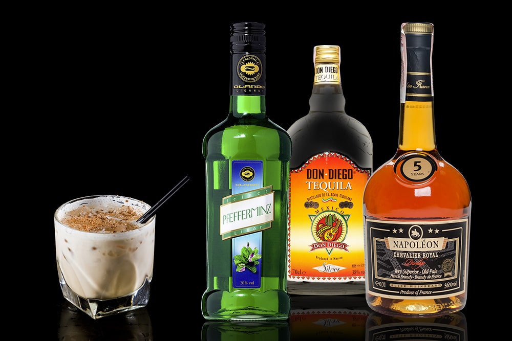 Асорті з пляшок лікеру, текіли, бренді та вершковий коктейль на чорному фоні