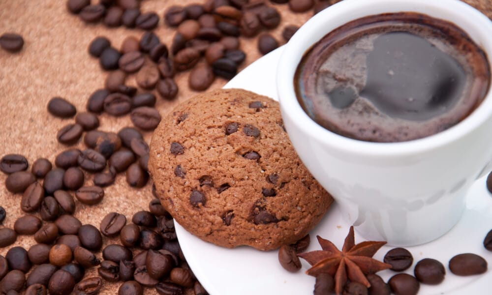Кава в чашці з печивом і зернами кави