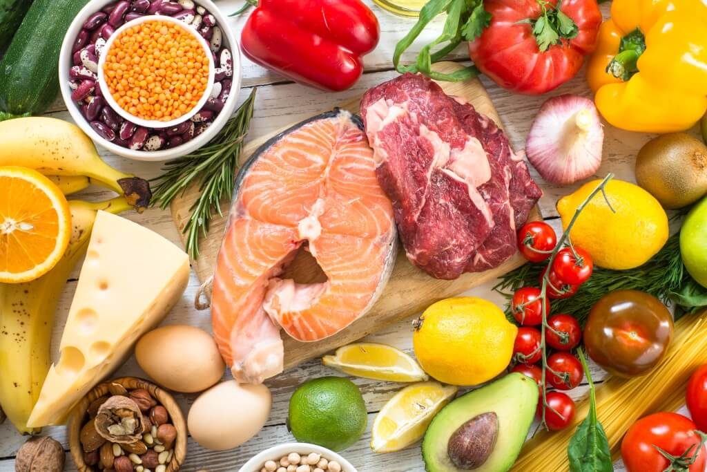 Набір білкових і вітамінних продуктів: м’ясо, риба, овочі, фрукти, яйця, сир, бобові, авокадо та зелень